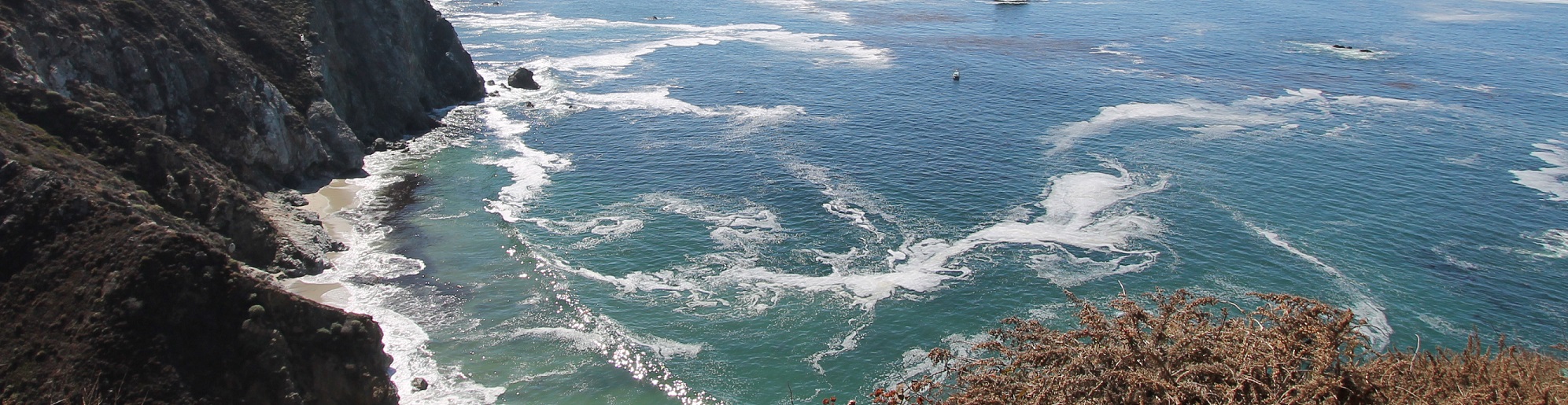 Sunlight over waves along a rocky coastline